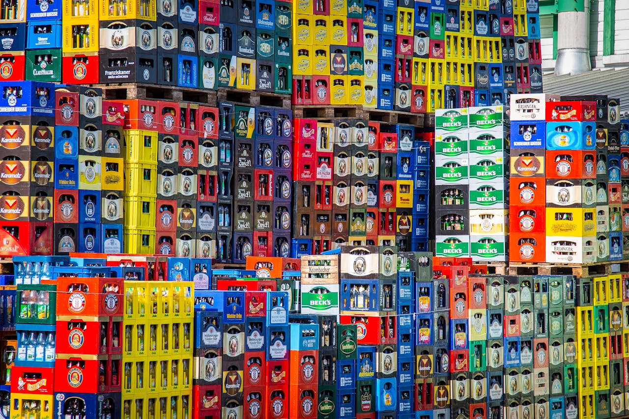 Home A vibrant display of beer crates stacked in a warehouse, showcasing various brands.